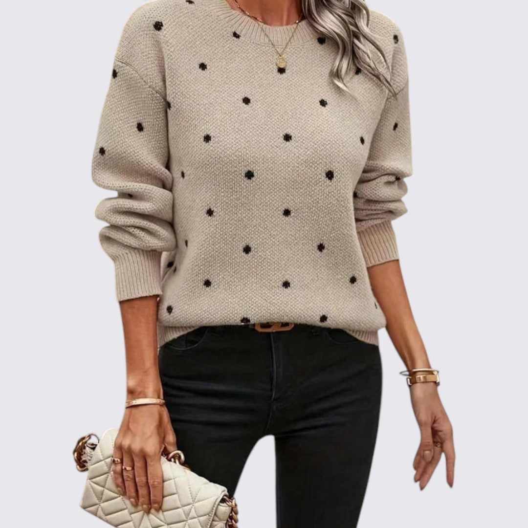 Woman in a beige crew neck knit sweater with small black polka dots, styled with black jeans