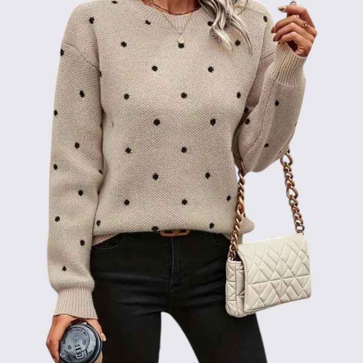 Woman in a beige crew neck sweater with small black polka dots and black jeans