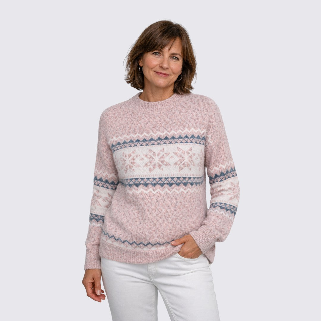 Pink knit sweater with a white and blue snowflake pattern band, worn with white jeans