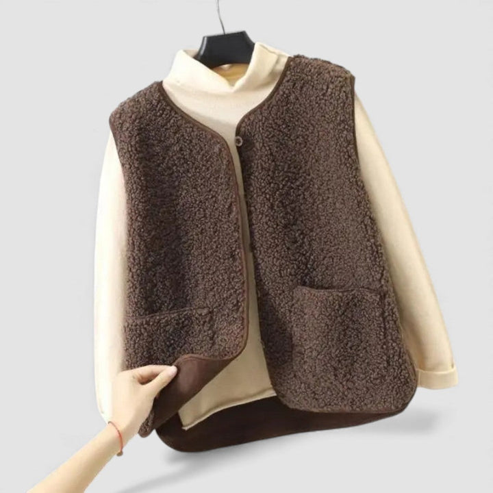 Brown teddy fleece open front vest with patch pockets on a hanger, worn over a cream sweater