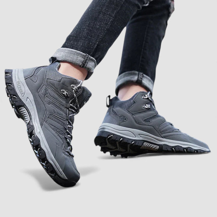 Grey lace up hiking shoes with black rubber lug sole worn with jeans, side view