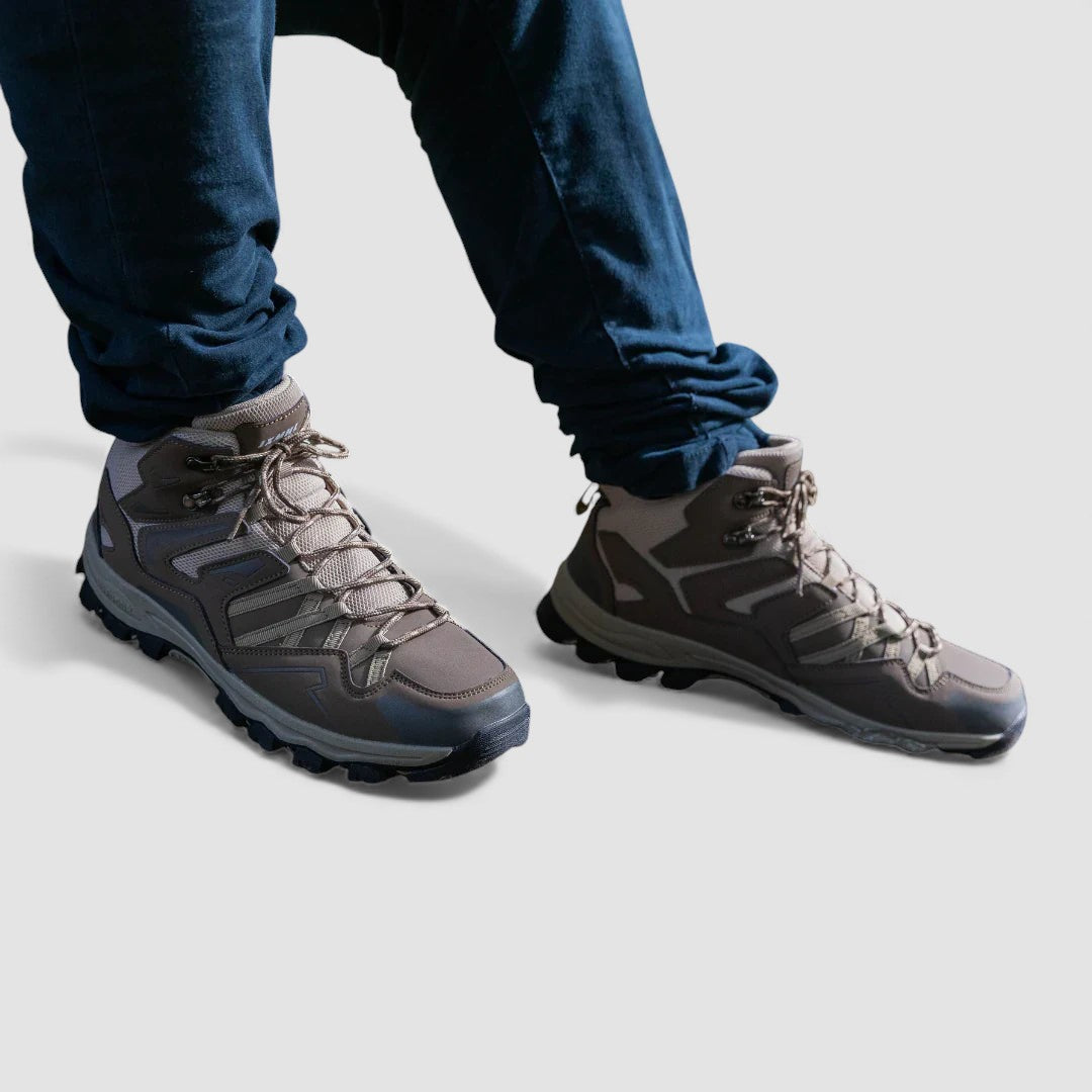 Grey and taupe lace up hiking shoes worn with dark blue jeans, seen from the front