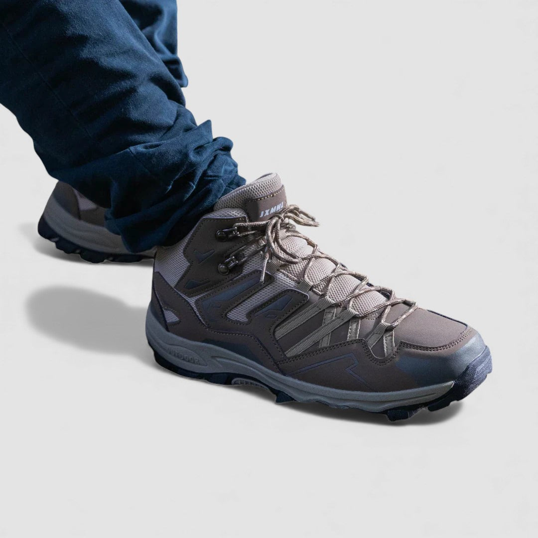 Side angle of a grey lace up hiking shoe with a padded collar worn with dark jeans