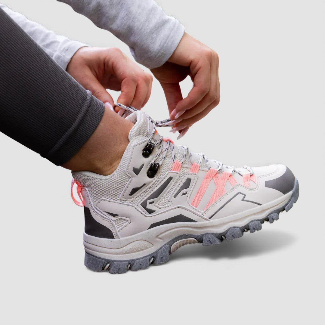 White and grey hiking shoe with pink laces and lug sole, side view being laced
