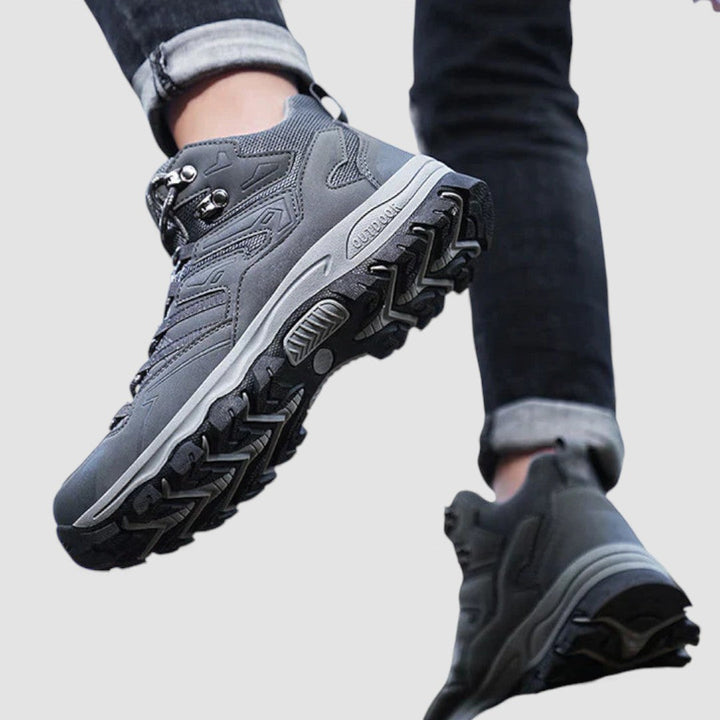 Gray hiking shoe mid stride, showing the deep treaded rubber outsole