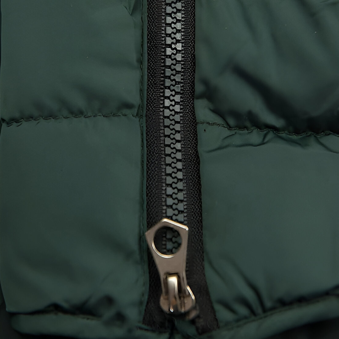 Close up of the dark green quilted fabric and the front zip pull of the jacket