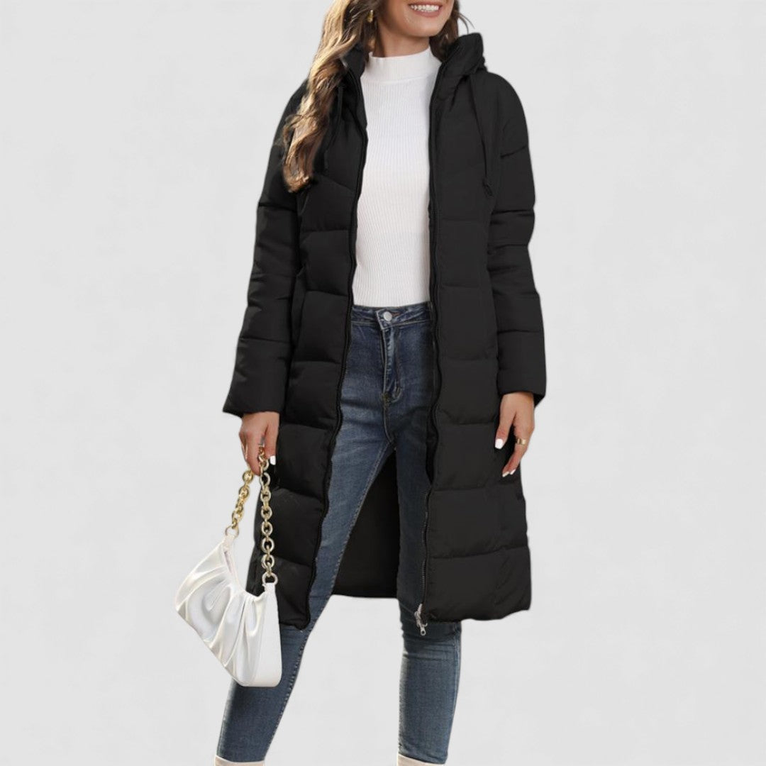 Woman in an open black quilted hooded puffer coat with a long knee length cut, worn over jeans