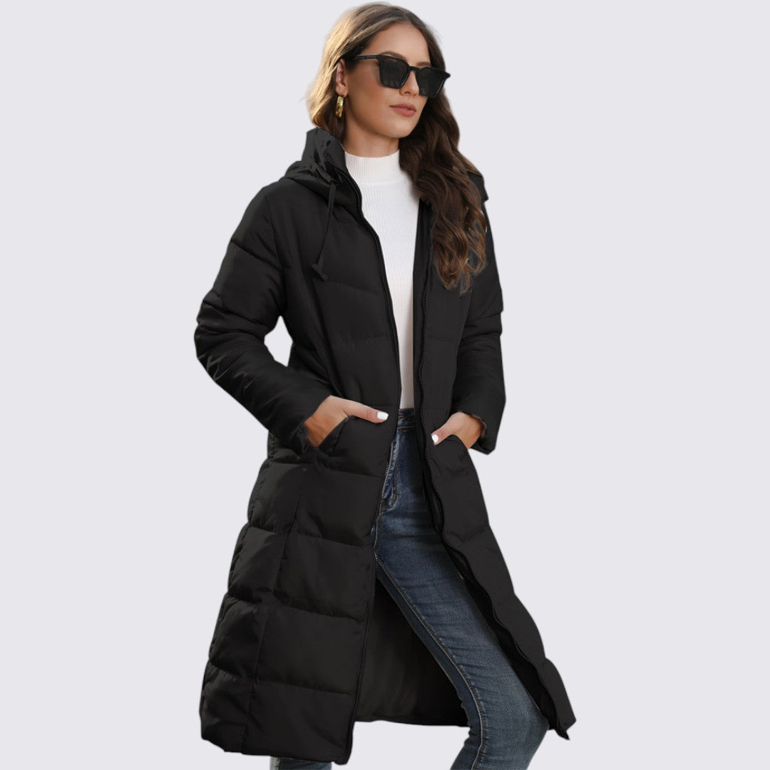 Woman in a long black quilted hooded puffer coat worn open over jeans, side view