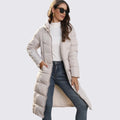 Woman in a beige long quilted hooded puffer coat worn open over jeans and a white top