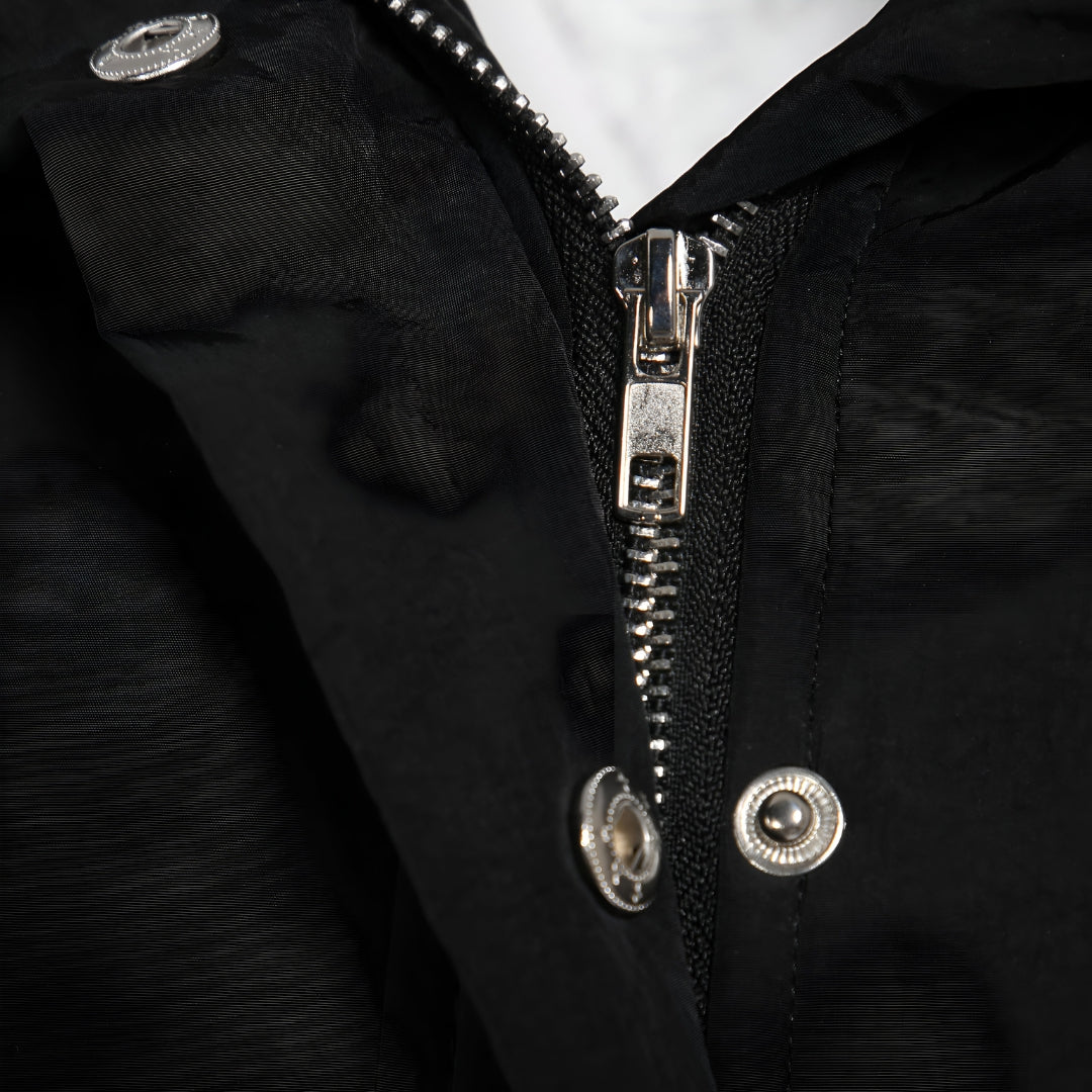 Close up of the zip and snap button placket on a black hooded parka