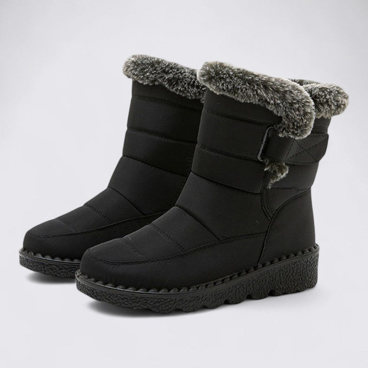 Pair of black padded snow boots with faux fur cuff and thick lug sole, angled view