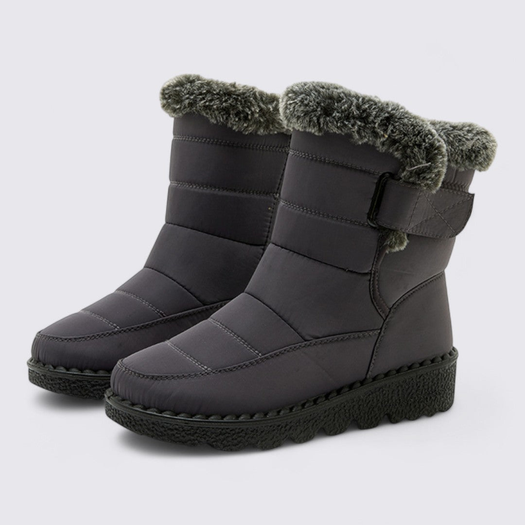 Pair of dark grey padded snow boots with faux fur lined cuffs and thick treaded soles, angled view