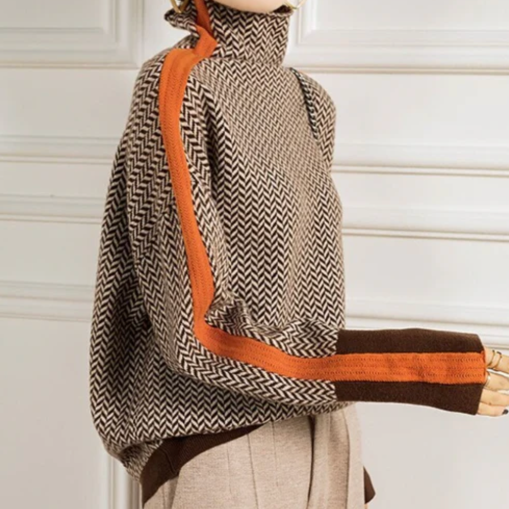 Side view of a brown herringbone turtleneck sweater with an orange stripe down the sleeve