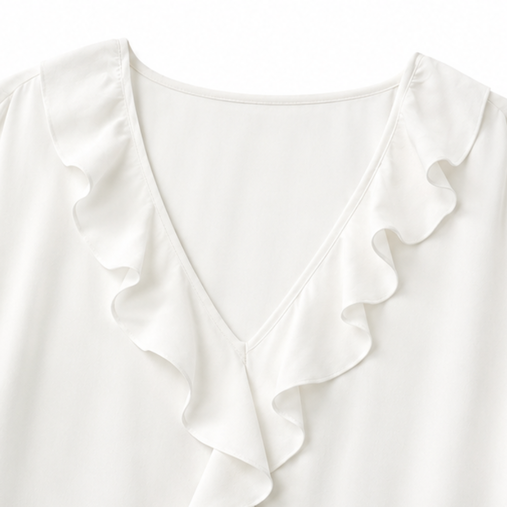 Close up of a white blouse V neckline with a soft ruffle trim placket
