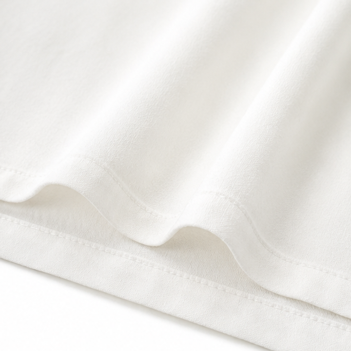 Close up of the fine stitching and soft drape of the white blouse fabric