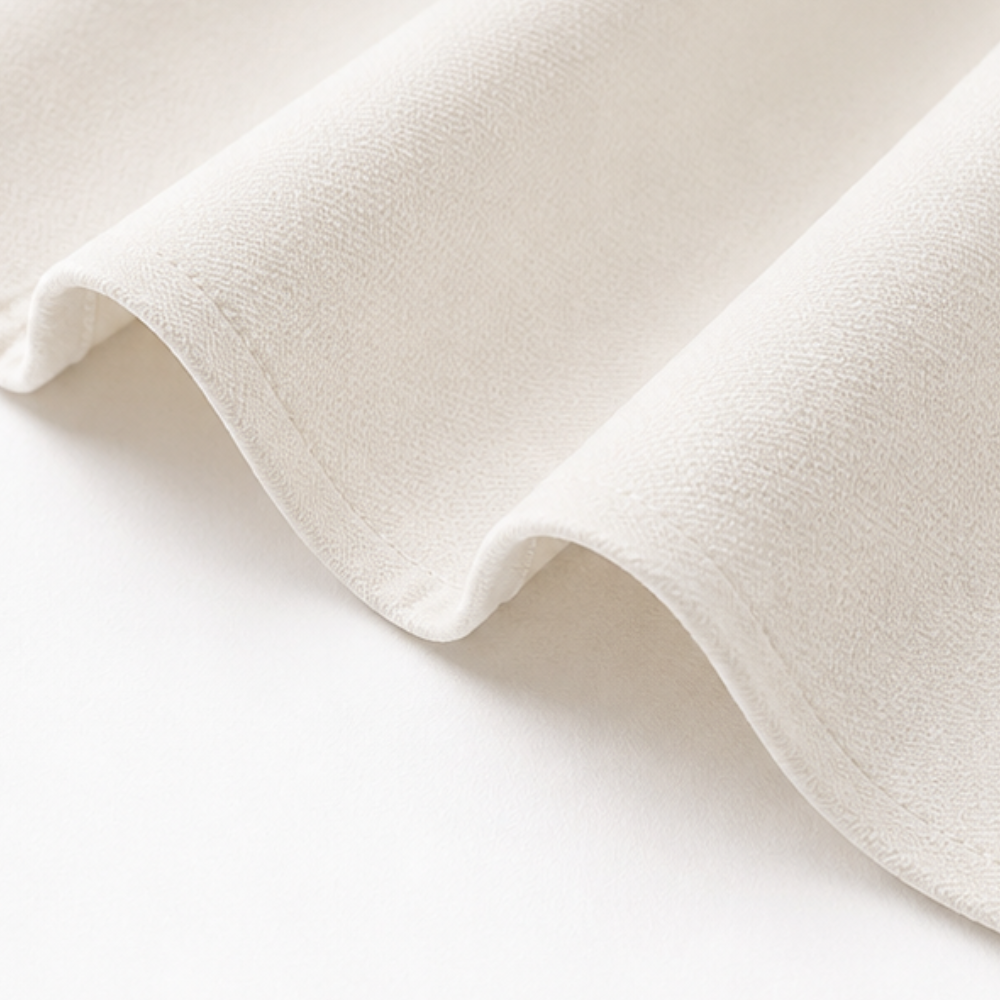 Close-up of the ivory woven fabric and stitched hem of the midi dress