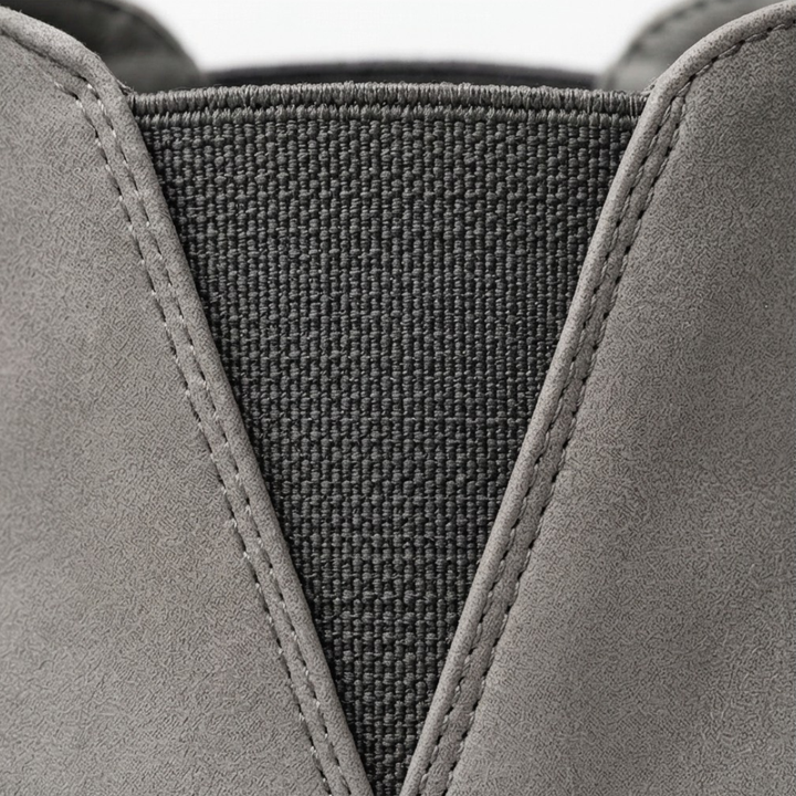 Close-up of the grey suede boot's elastic side panel and stitching