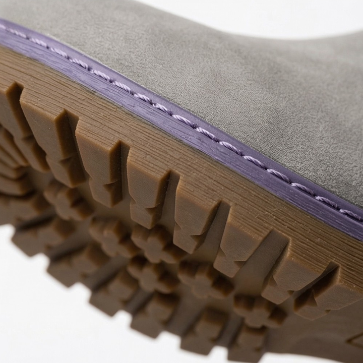 Close-up of the grey ankle boot upper with lilac stitching and a tan lug sole