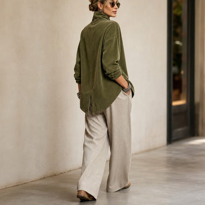 Olive green corduroy top, back view walking in wide cream pants