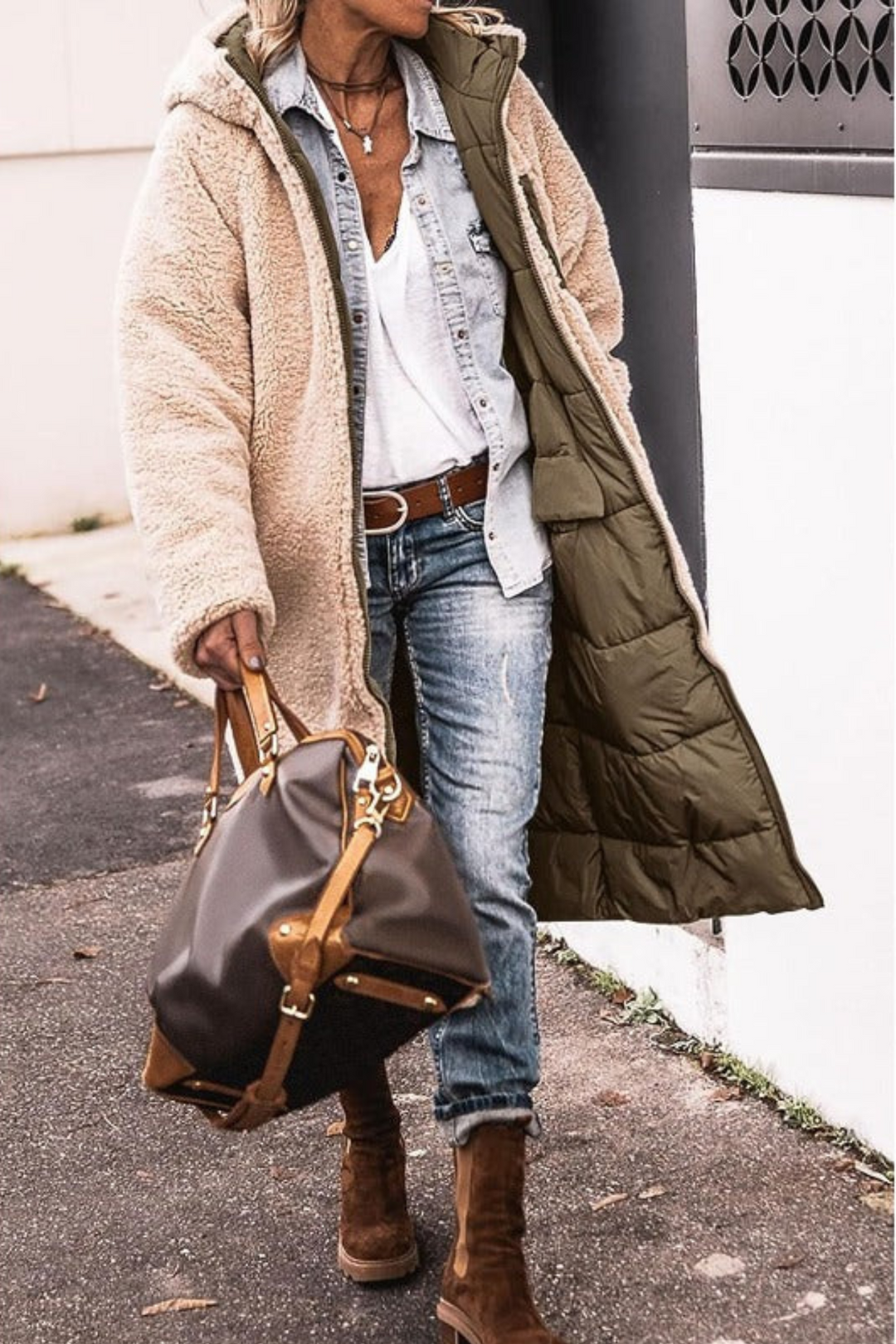 Woman outdoors in a longline coat worn on the cream teddy side with the olive quilted lining showing