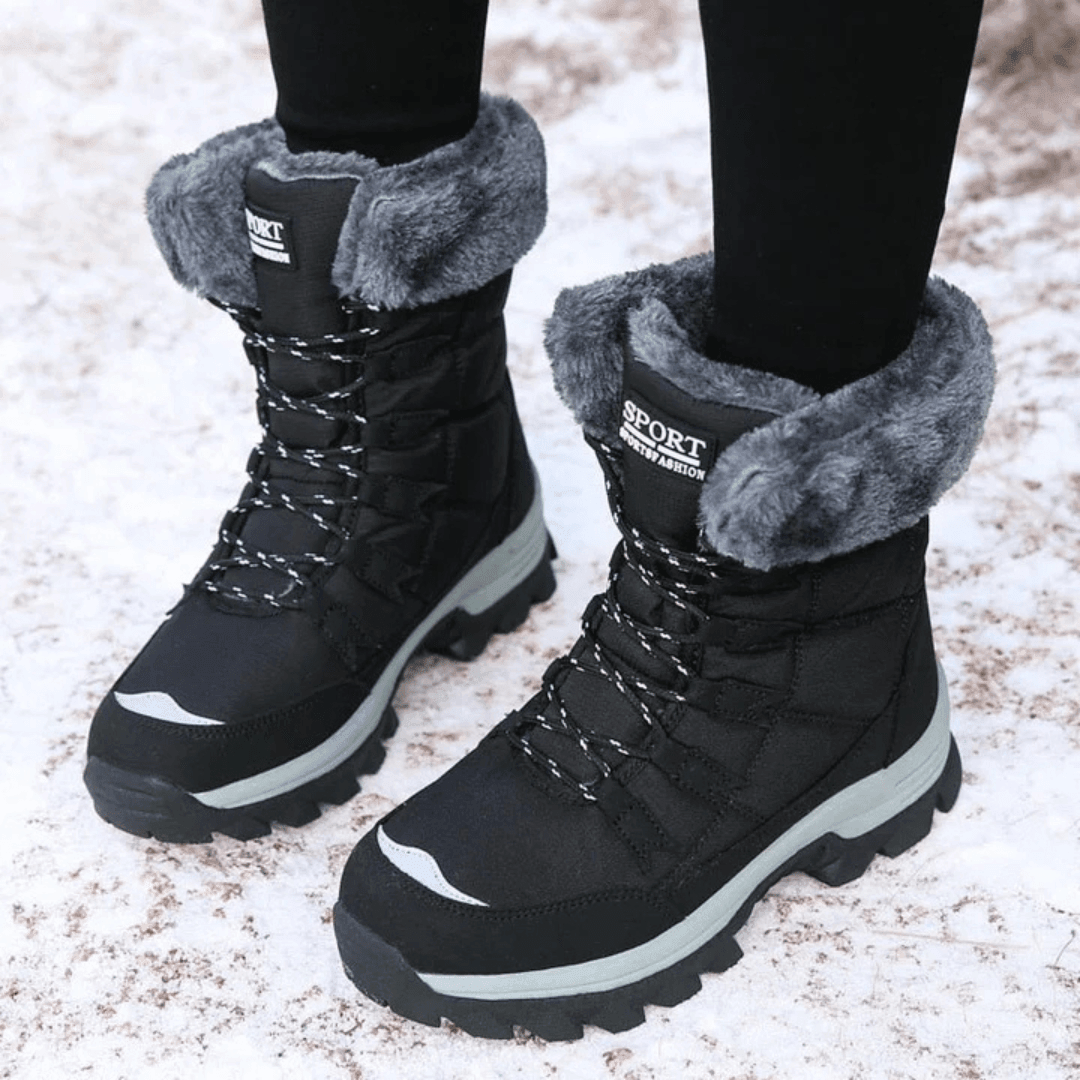 Black lace up boots with a grey cuff on a cleated sole in snow