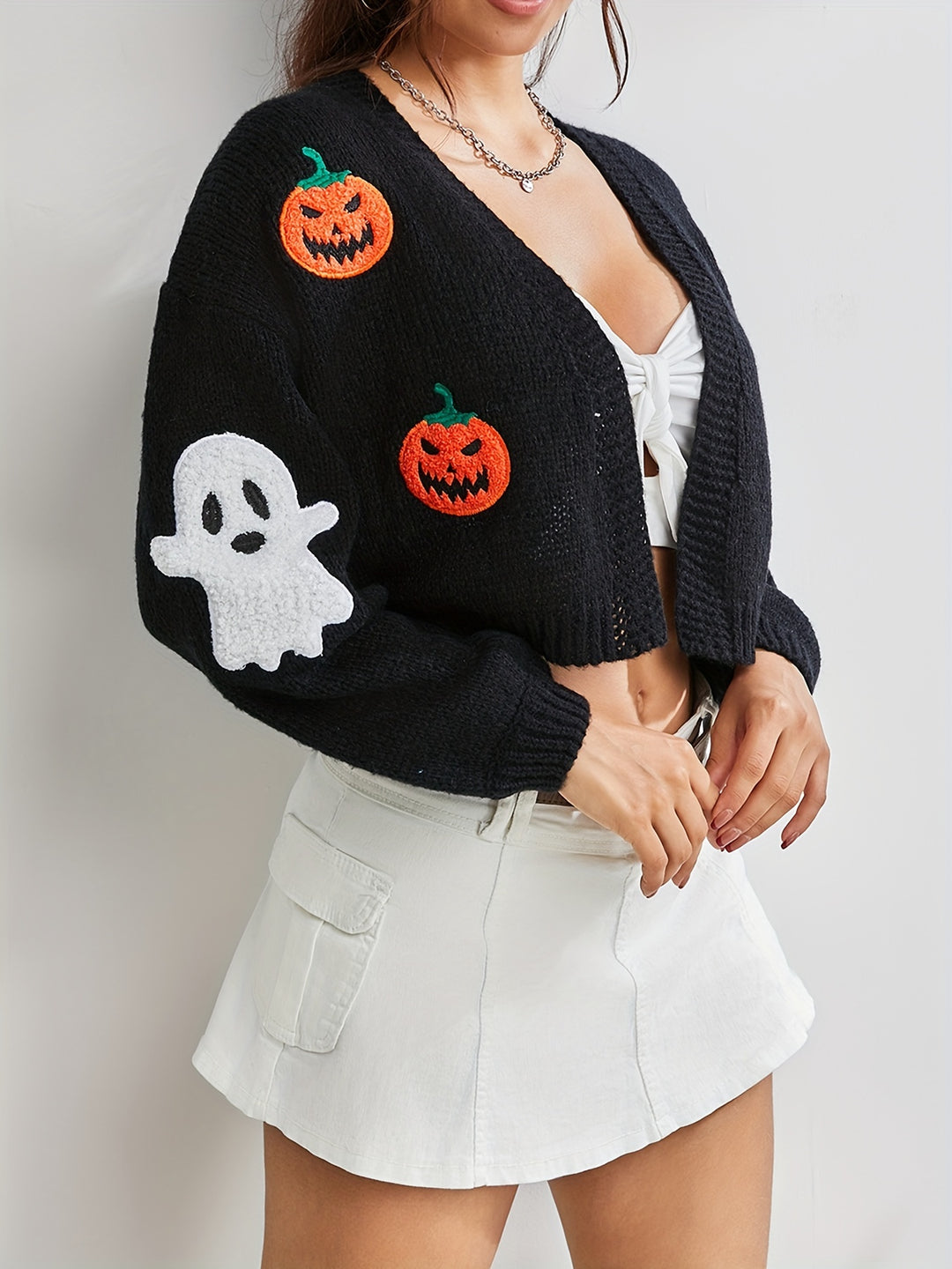 Cropped black knit cardigan with orange pumpkin and white ghost patches, open front