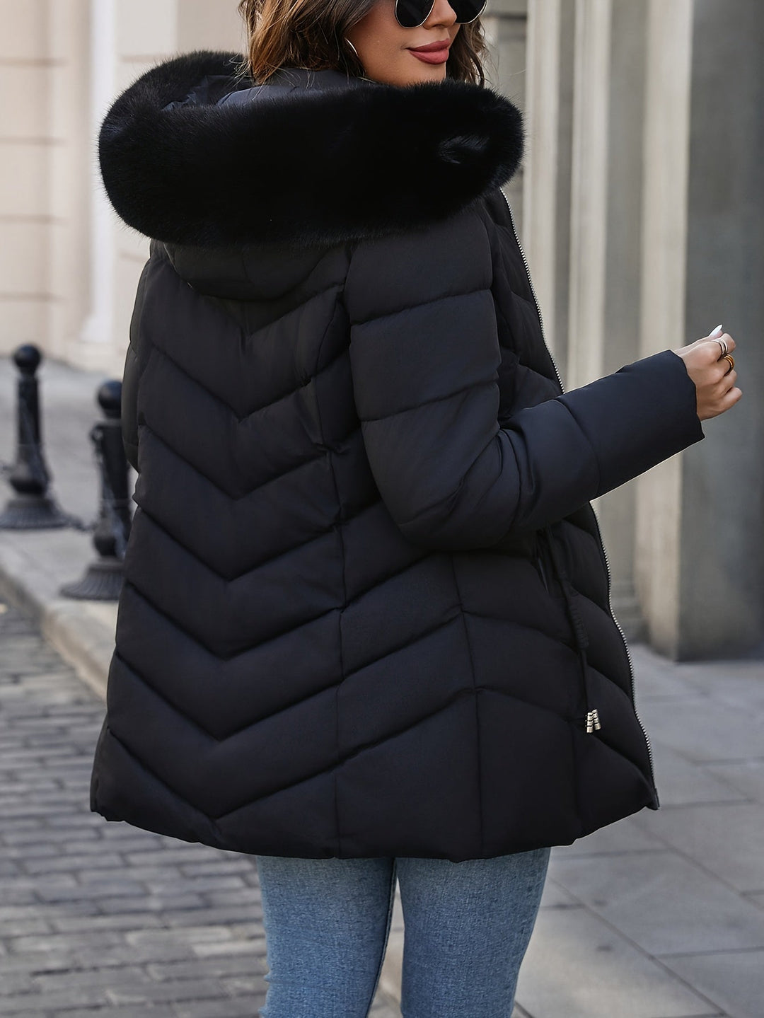 Black quilted coat seen from the side with the fur hood up