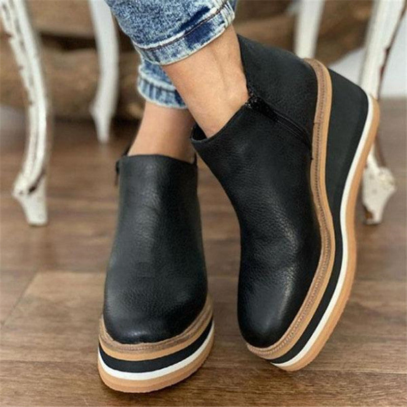 Black leather ankle boots with a striped platform sole worn with jeans