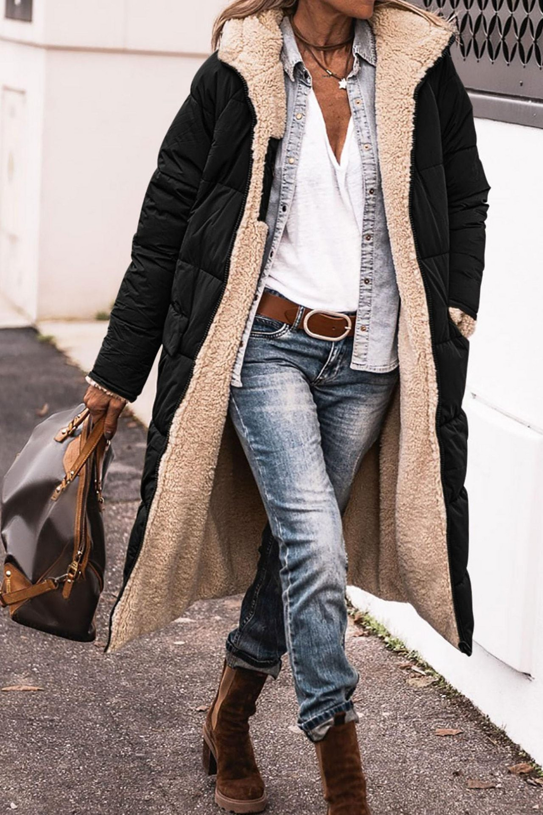 Black longline coat worn open on the street, showing the cream faux shearling lining