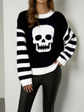 Black knit sweater with a white skull motif and black and white striped sleeves, front view