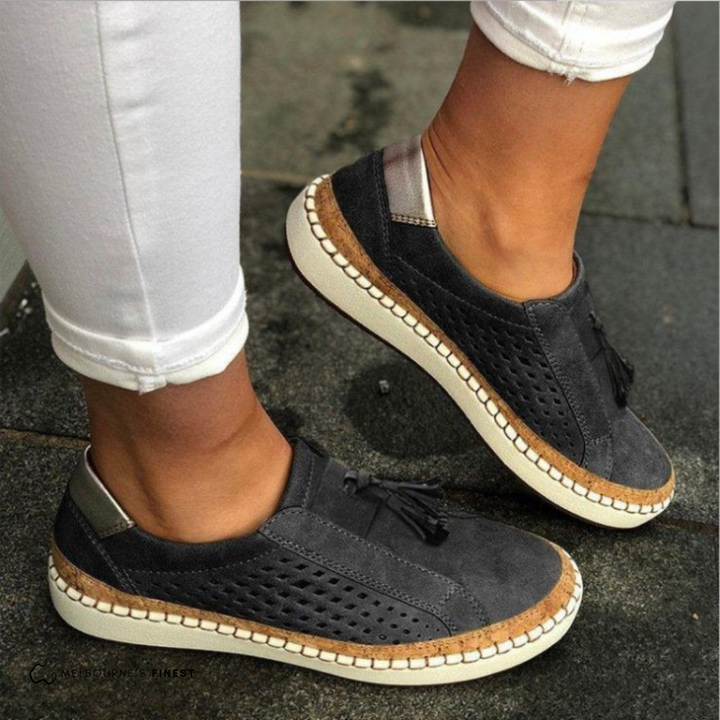 Black slip on sneakers with perforated panels and a tassel