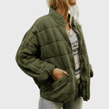 Olive box quilted bomber jacket worn open over a knit top, front view