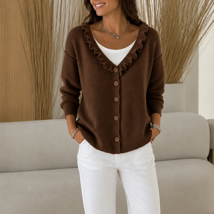 Brown ruffle trim knit cardigan with wooden buttons worn over a white top and white jeans