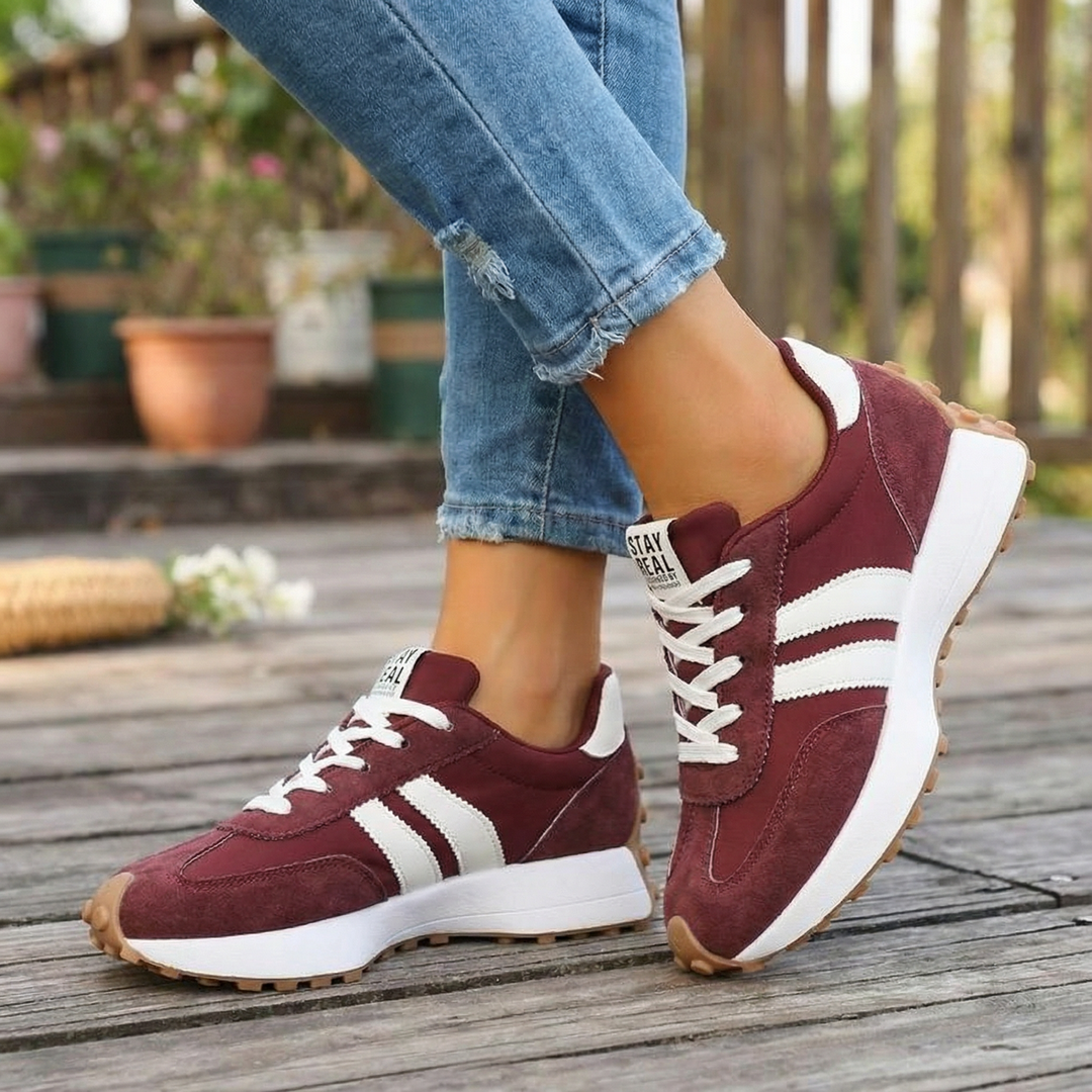 Burgundy suede sneakers with white side stripes and a gum sole, worn with cropped jeans