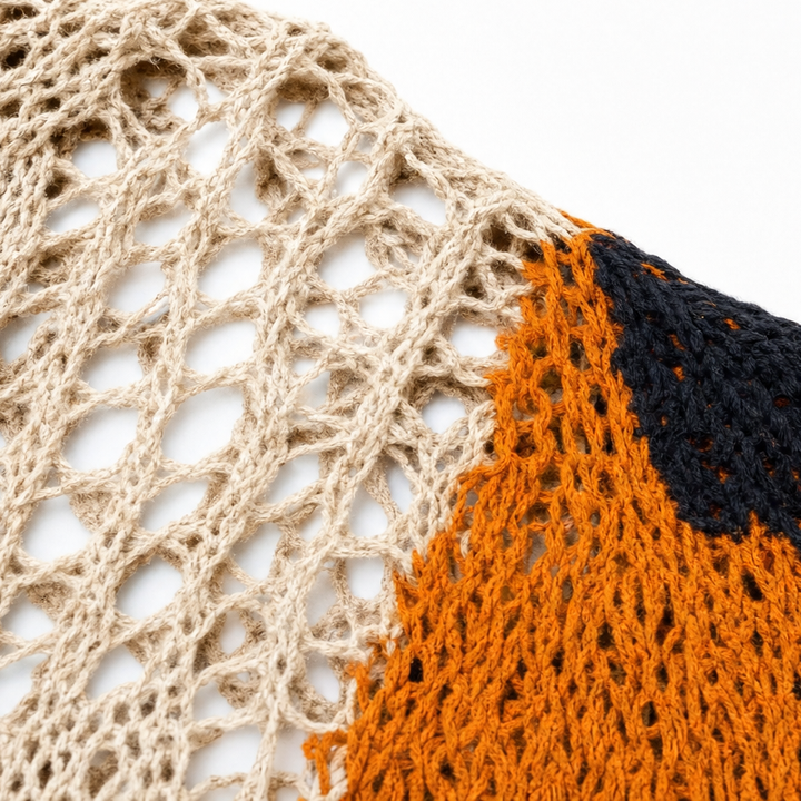 Close up of beige open knit fabric with an orange and navy pumpkin motif
