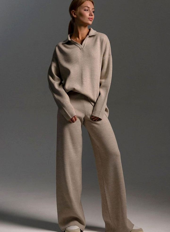 Woman wearing a beige two piece lounge set with a collared knit top and wide leg trousers, full length