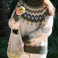 Cream knit sweater with an olive green Nordic fair isle yoke pattern, worn outdoors