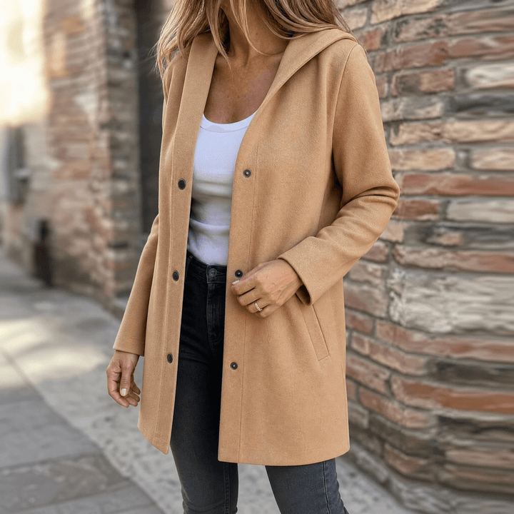 Woman wearing an open camel hooded cardigan jacket with black jeans on a city street