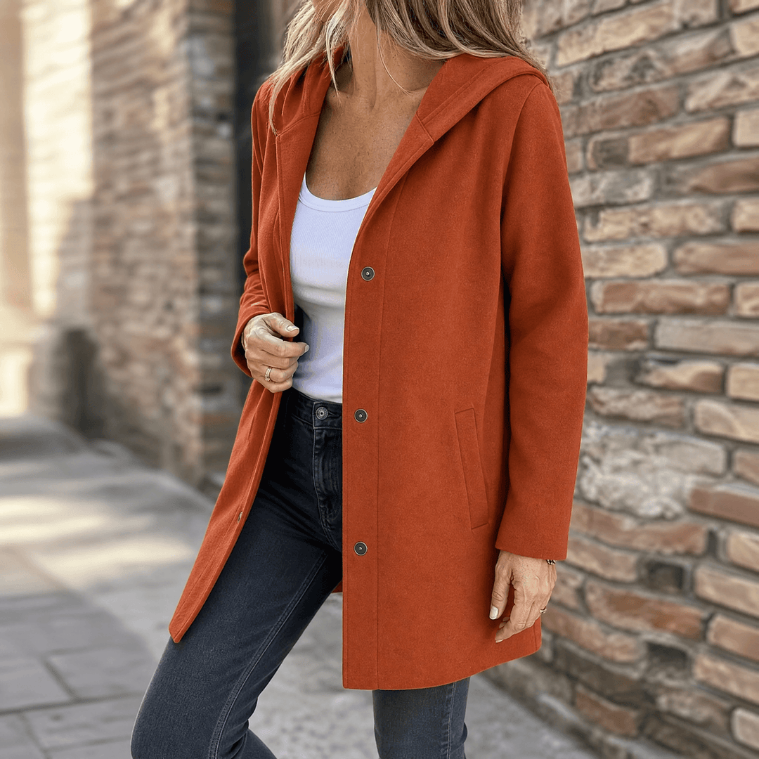 Rust hooded longline jacket with a button front and side pockets, worn open over jeans, side view