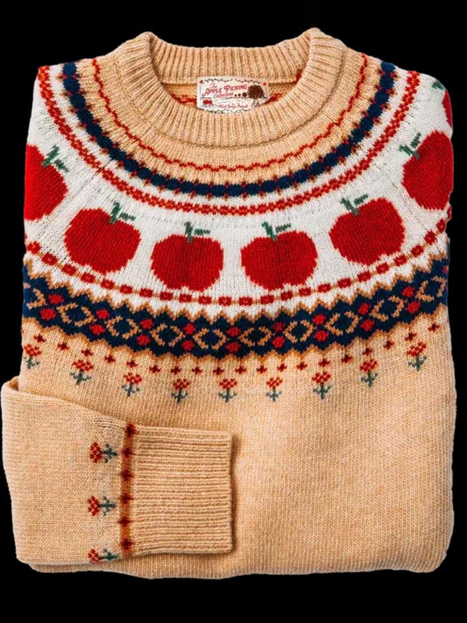 Folded cream knit sweater with a red apple and navy fair isle yoke pattern