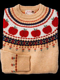 Folded cream knit sweater with a red apple and navy fair isle yoke pattern