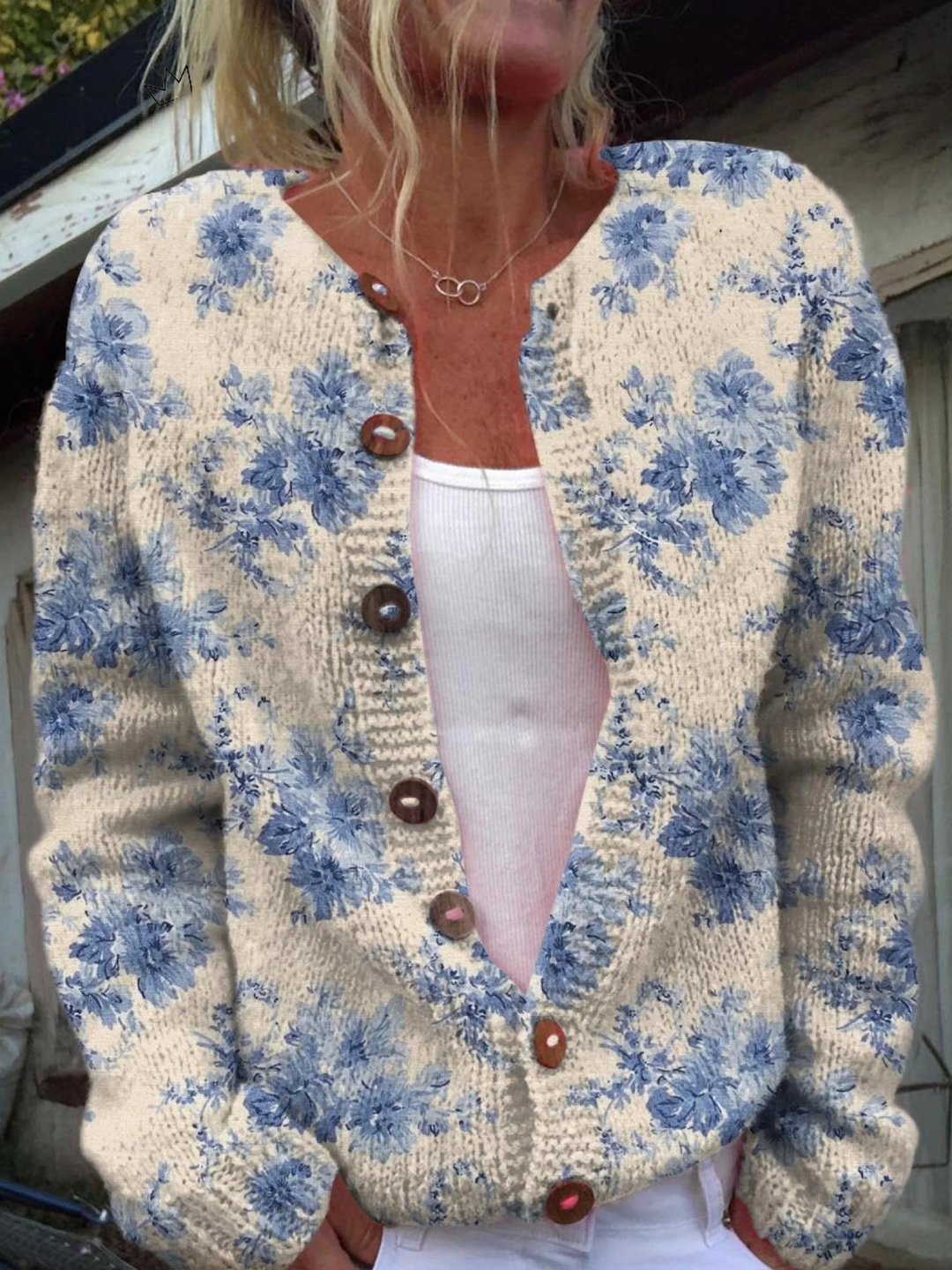 Cream knit cardigan with a blue floral print and wooden buttons, worn open over a white top