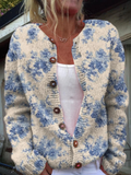 Cream knit cardigan with a blue floral print and wooden buttons, worn open over a white top