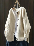 Cream cable knit cardigan with wooden buttons, shown on a hanger against dark wood panelling