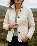 Cream diamond quilted jacket with a stand collar, worn outdoors