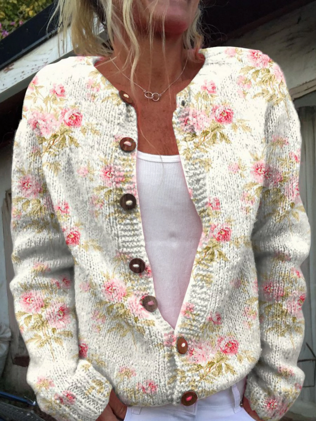 Cream knit cardigan with pink rose print and brown buttons, worn open over a white top
