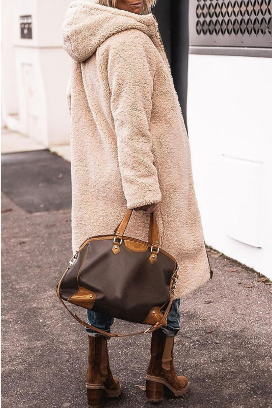Back view of a woman in a long cream teddy fleece hooded coat, styled with jeans and brown boots