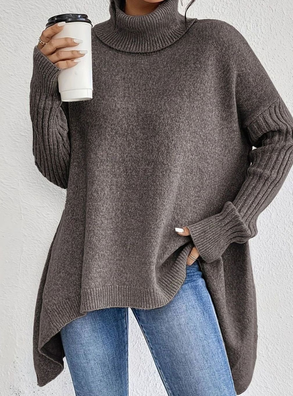 Woman in an oversized dark brown turtleneck sweater with a longline hem and jeans