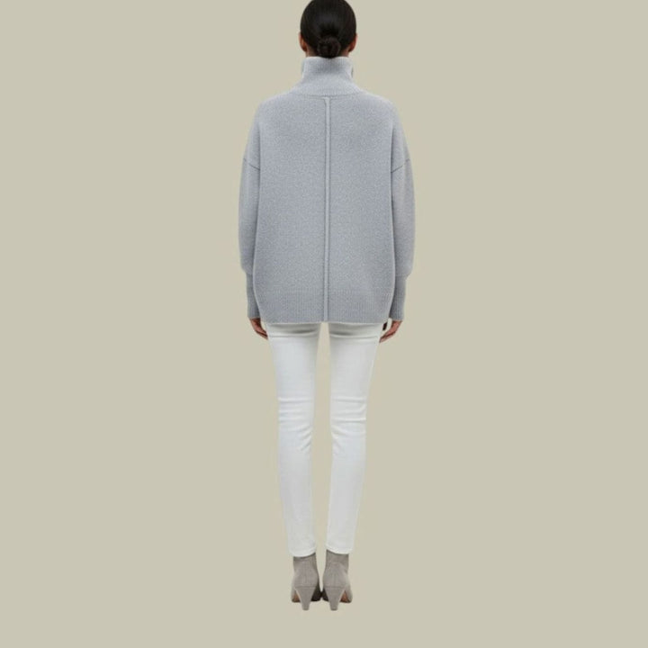 Back view of a light gray oversized turtleneck sweater with white jeans