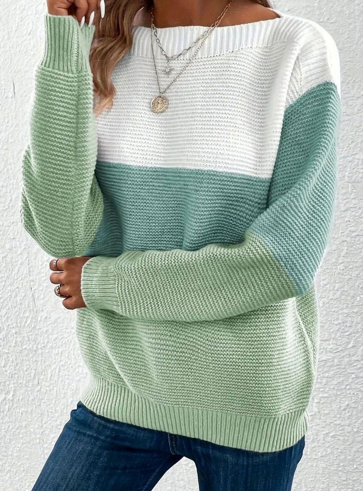 Woman wearing a green and white color block knit sweater with a wide boat neckline